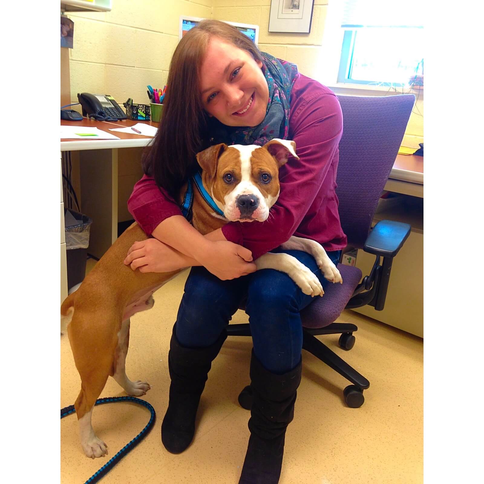 A staff member says "goodbye" to her foster dog who was adopted after going through surgery for a leg wound.