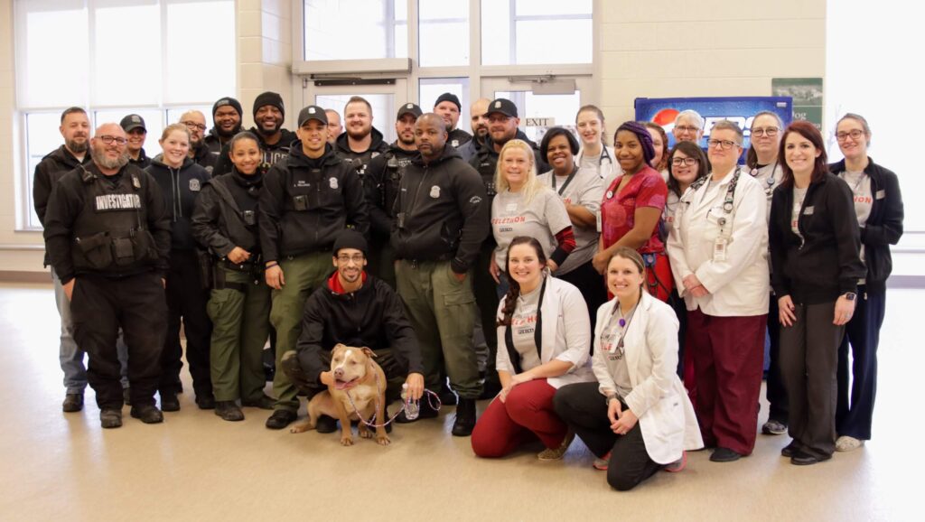 MHS medical staff poses with dog and his owner, Detroit police.