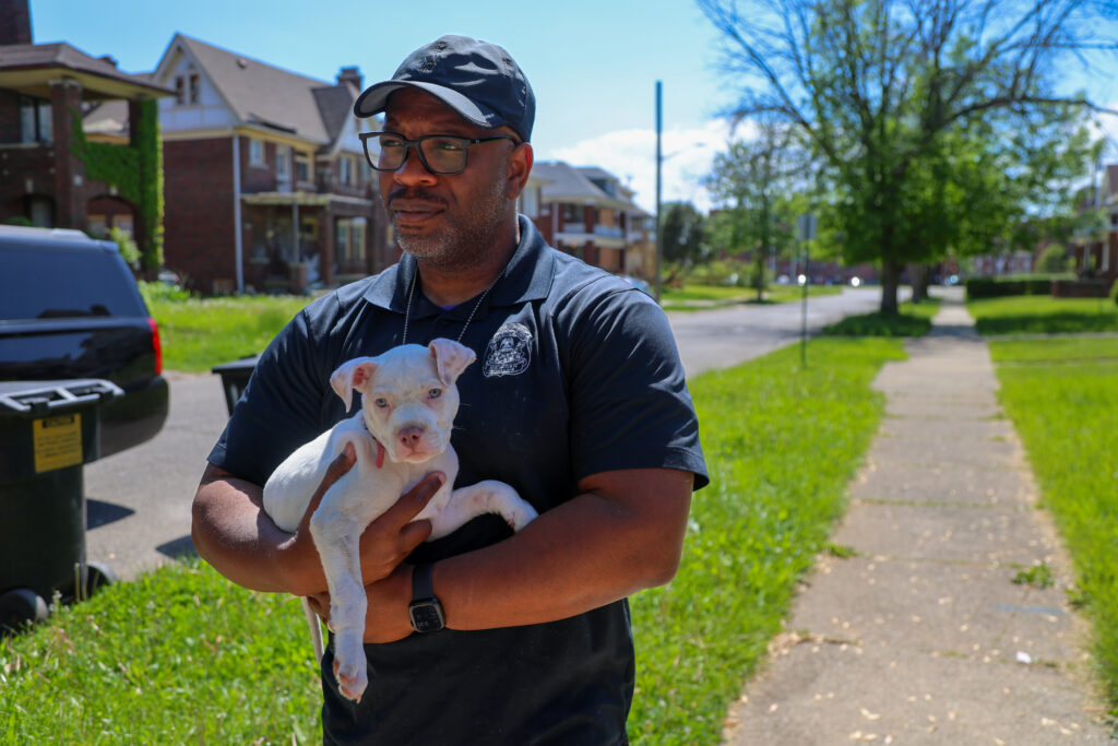 Person with hat and glasses holding a puppy